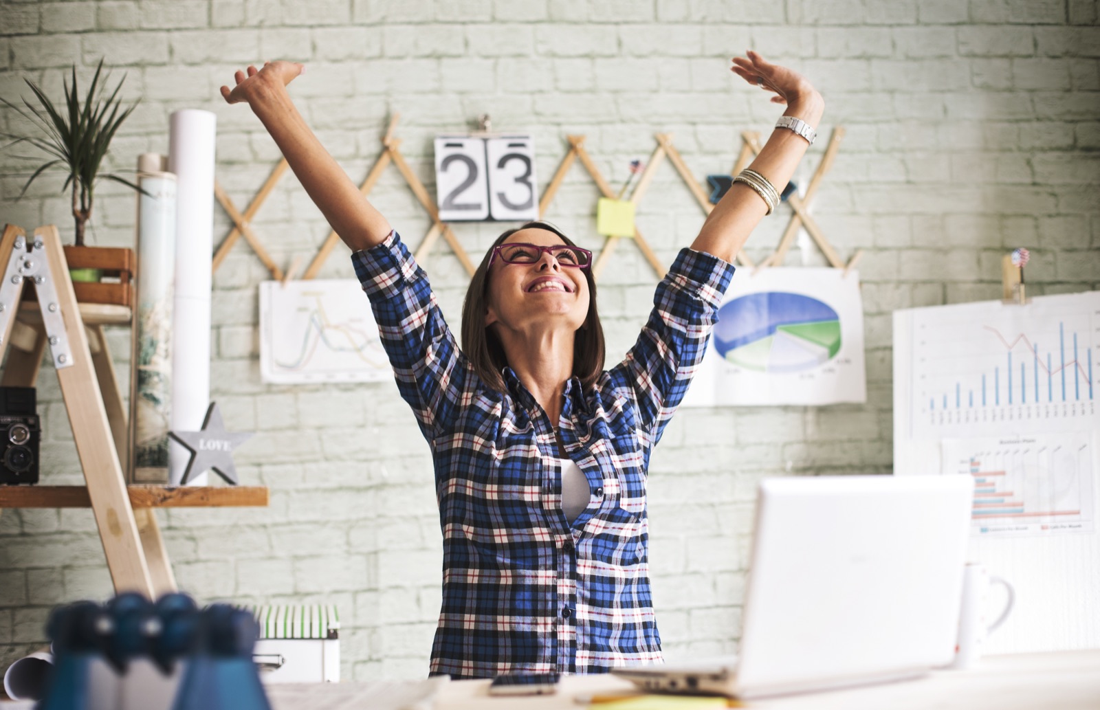 Une femme lève les bras de joie à son bureau