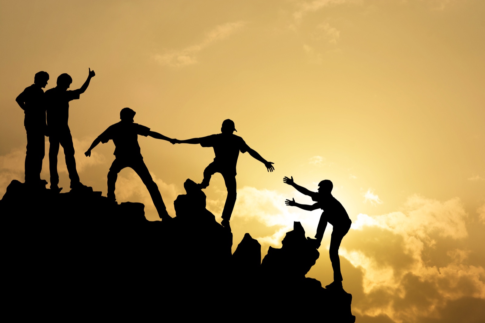 Silhouettes qui s'entraident pour gravir un sommet